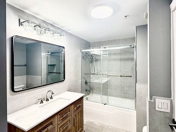 Newly remodeled bathroom featuring modern fixtures and elegant floor-to-ceiling finishes throughout.