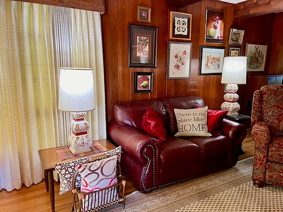 Furnished living room with leather sofa, recliner, mid-century decor, wood floors, beamed ceiling, 9 x 12 area rug.