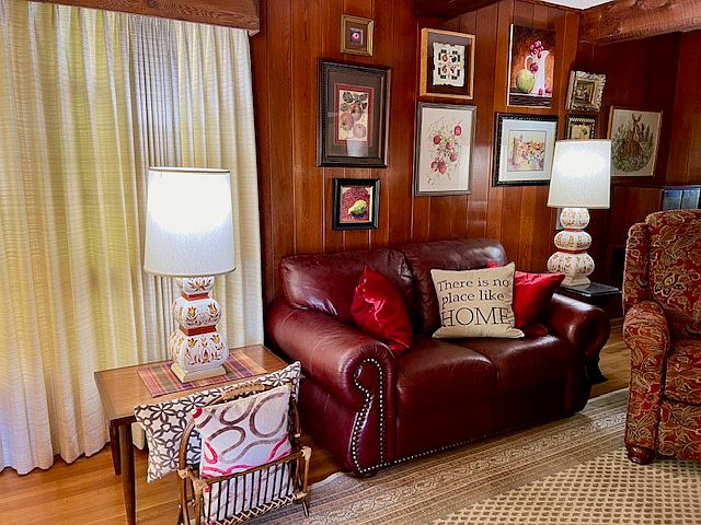 Furnished living room with leather sofa, recliner, mid-century decor, wood floors, beamed ceiling, 9 x 12 area rug.