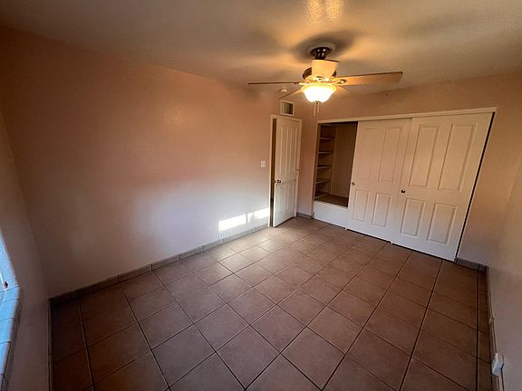 Spacious main room with ceiling fan and window with backyard view.
