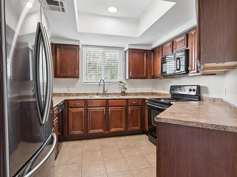 Nice kitchen with reset lighting above, microwave, oven, dishwasher and side by side fridge