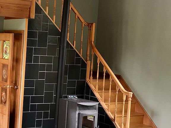 Living room with pellet stove. Stairs lead up to office.