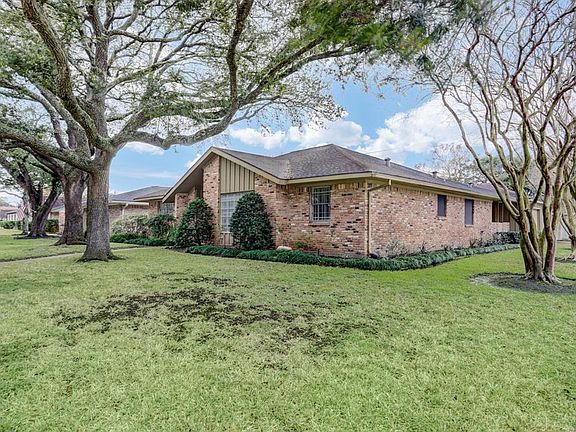 Spacious front lawn wraps around corner with detached garage entry on side. Beautiful live oak trees grace the property.