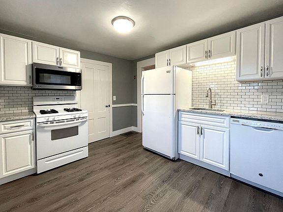 Eat in kitchen with granite countertops, dishwasher, gas stove, microwave and subway tile backsplash.