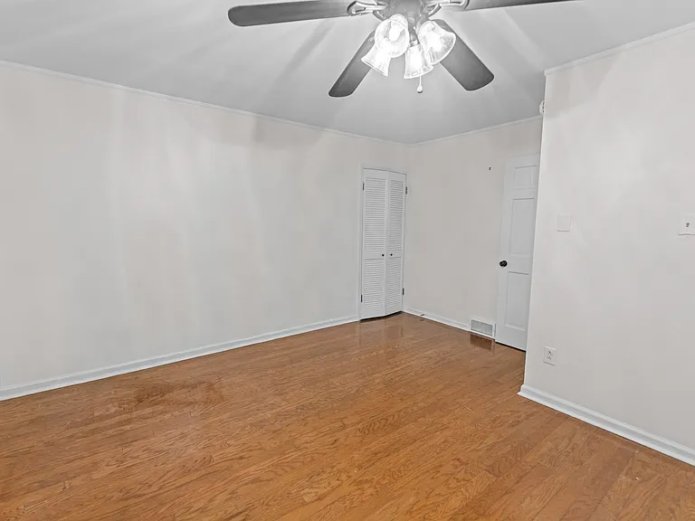 Generously sized bedroom with warm hardwood floors, ceiling fan, and dual closets _ ample storage for everyone.