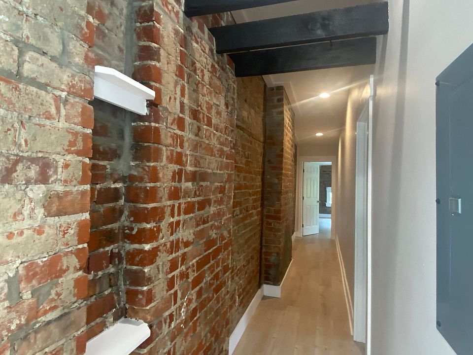 Exposed brick hallway runs throughout both walls that make up the length of the home