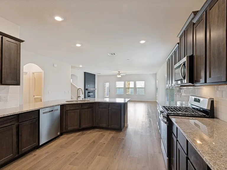 Spacious kitchen featuring dark wood cabinetry, light-toned countertops, and stainless steel appliances