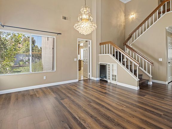 Open sitting and dining area with high ceilings and chandelier.