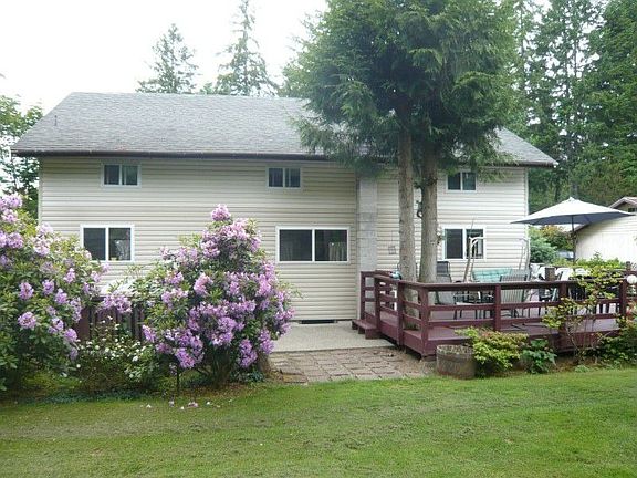 Rear of home with large wrap around deck and large concrete patio to the right of picture.....