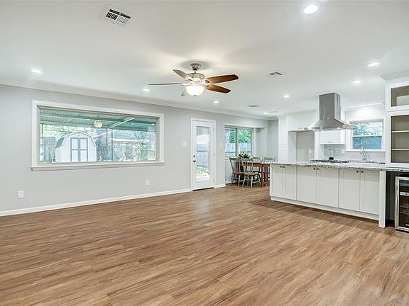 Living room/kitchen/breakfast area showing large picture window, glass cabinet doors, beverage cooler location, recessed lighting and ceiling fan.