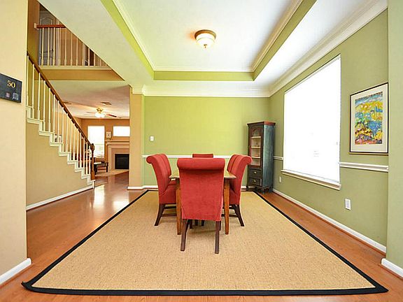 Elegant formal dining room with tray ceiling, accent walls and laminate flooring.