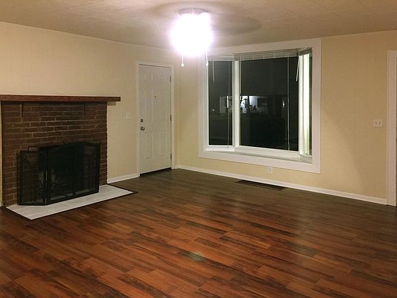 Large light-filled living room with bay window and electric fireplace.