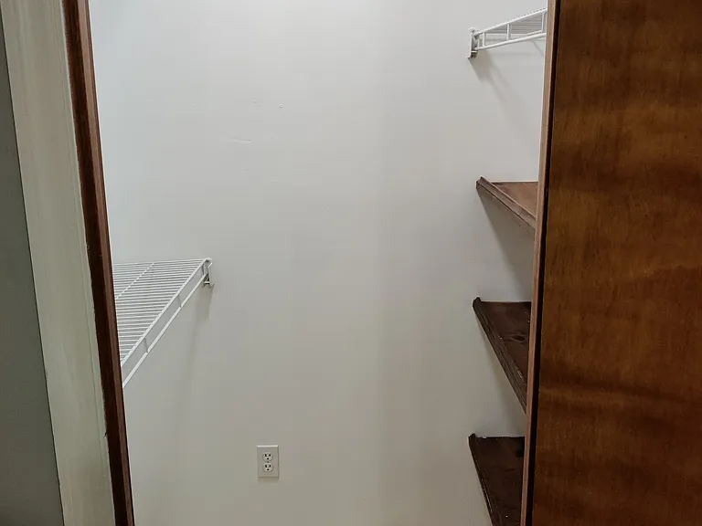 1st bedroom closet with wood floor and wooden shelves and led light.