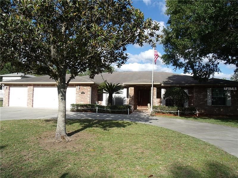 Front View from side walk showing circle driveway, covered entrance sidewalk, garages, landscaping