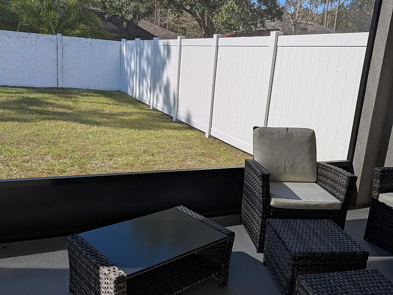 Screened porch off living room with outdoor furniture, overlooking a private fenced yard.