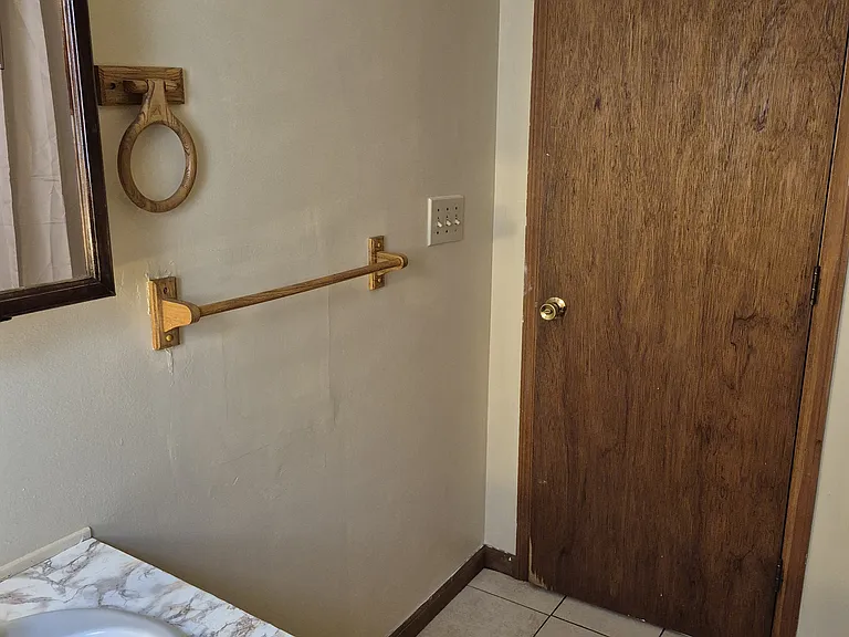 View inside bathroom from toilet alcove past sink toward door