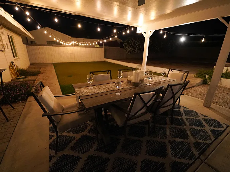 Outdoor living area is under a covered patio, with globe lights on timer