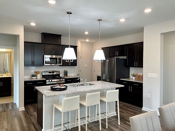 Photo from model home of same plan. Cabinets, countertop, backsplash, flooring, appliances will be the same. Pendant lights not included.