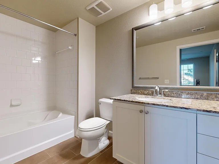Apartment bathroom with large soaking tub and wood-style flooring.