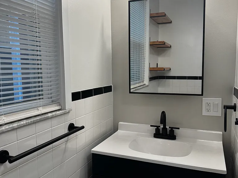 Bathroom (Actual Picture): Updated full bathroom with a tiled tub/shower, refreshed finishes, and convenient open shelving for extra storage