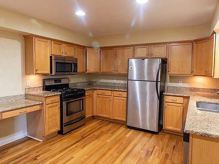 Bright and spacious kitchen featuring modern stainless steel appliances, elegant wooden cabinetry, and sleek granite countertops.