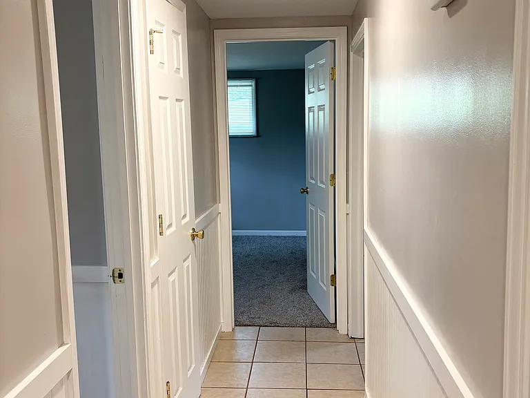 Downstairs hall leading to two bedrooms that share a bathroom. Also off of this hallway is shared storage room that attaches to laundry room. Garage door opens to this hallway.