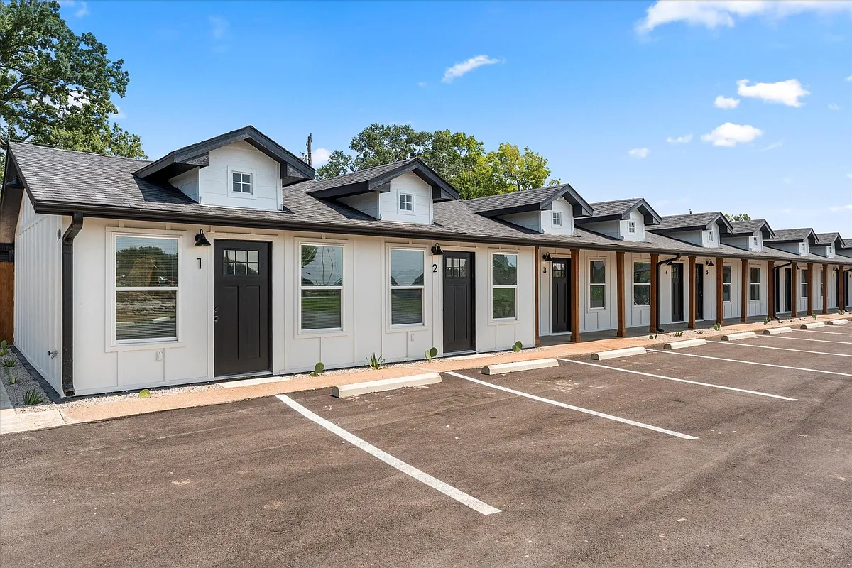 Modern farmhouse-style facade with white vertical siding, black trim, and dormer windows - 900 S Tool Dr #7