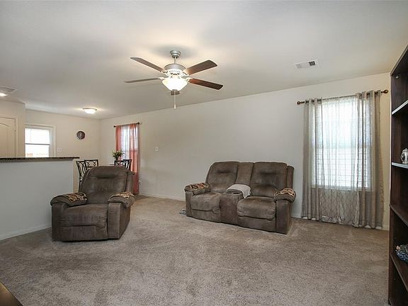 Another view of the family room shows the windows giving natural light into the family room and kitchen and ceiling fan.