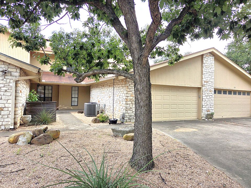 Front of townhome with attached 2 car garage and large shaded trees