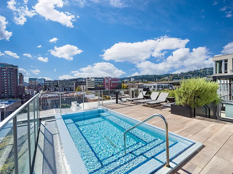 A rooftop pool at Modera Pearl with panoramic city views, sun loungers, and open decking designed for refreshing daytime breaks above Portland.