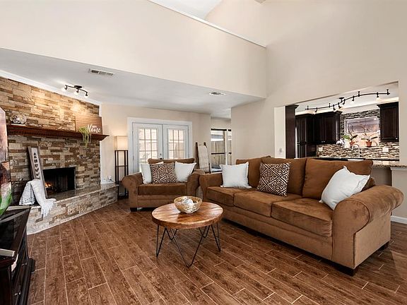 Cream and coffee-colored tones welcome you into the main living space with a gorgeous fireplace framed by stone and a wood-look tile floor beneath you.