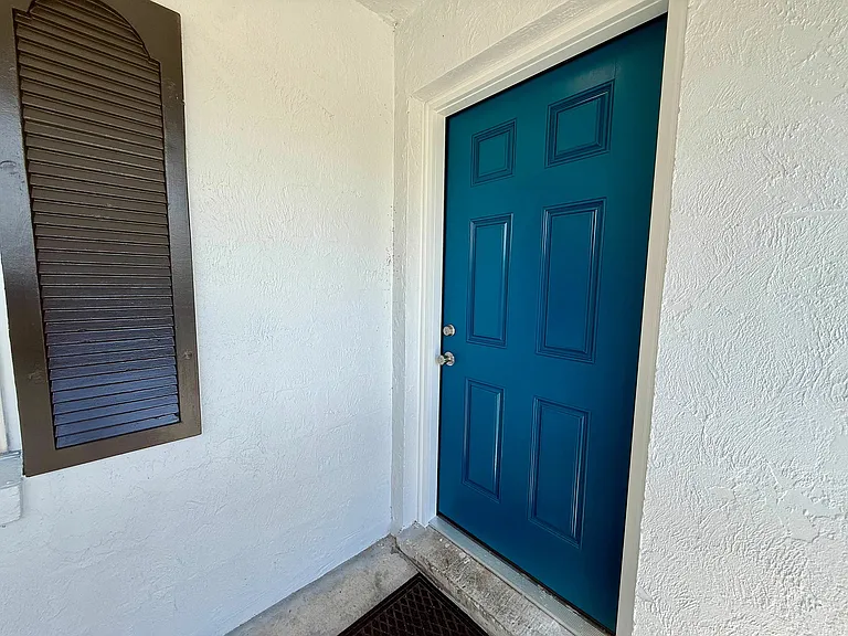 Charming entrance with a vibrant blue door and sleek wall shutters, perfect for a welcoming ambiance.