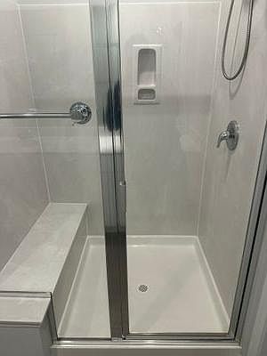 Walk-in shower with sliding glass doors, built-in soap niche, and easy-clean surround for everyday convenience.