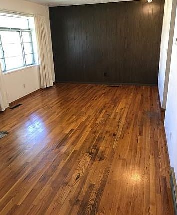 View of living room and front window from hallway to the bedrooms. Natural wood floors!