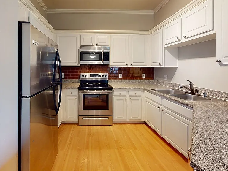 Apartment kitchen with wood-style flooring and stainless steel appliances in select homes.