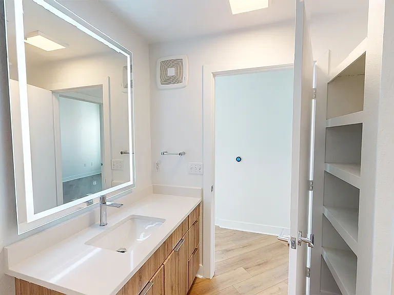 Apartment bathroom with wood-style flooring and an LED vanity mirror.