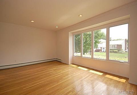 Lovely sunlit livingroom w/ hardwood floors and crown moldings