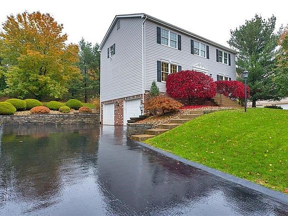 Large paved driveway with omni stone wall entering into the 2 car garage.