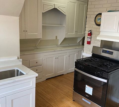 Kitchen stove, cabinet, and sink.