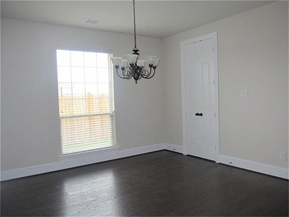 Dining room with elegant chandelier, wood floors and door that leads to the kitchen