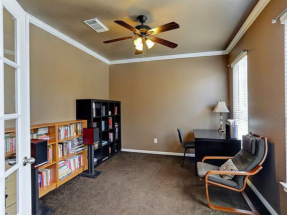 As you enter the home on the right side is a study with French Doors. The room features neutral walls, two windows ceiling fan, and crown molding.
