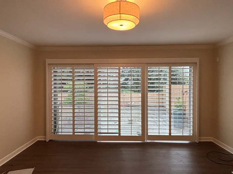 Wall of sliding doors with plantation shutters opening to backyard