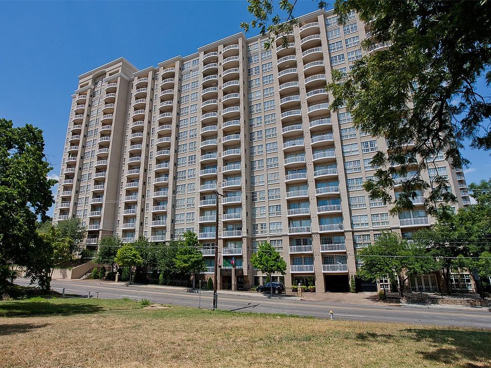 Multi-story residential building featuring a light-colored facade and numerous private balconies with white railings