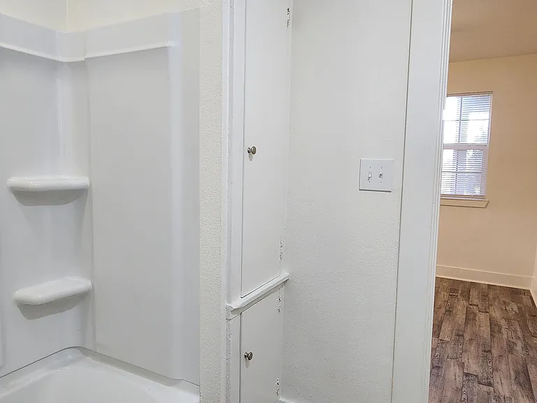 Bathroom with tub/shower combination and linen closet storage.