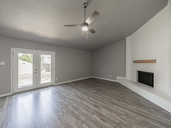 Living room with new ceiling fan and mantle. New french doors lead to back yard.