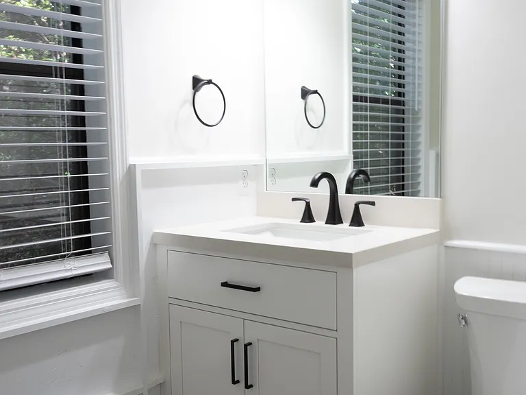 The newly-renovated bathroom features a new vanity and toilet with coordinated matte black fixtures.