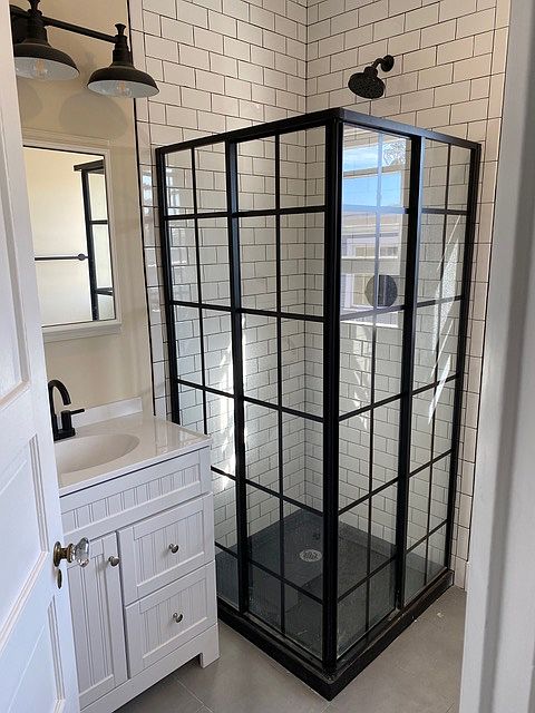 metal and glass shower enclosure and remodeled bath