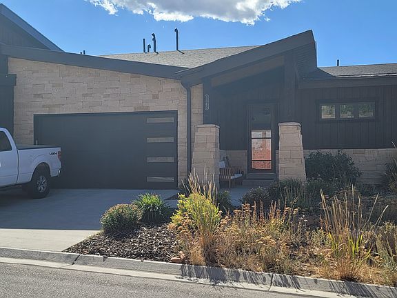 End unit front view, with 2 car garage and front covered outdoor sitting area.