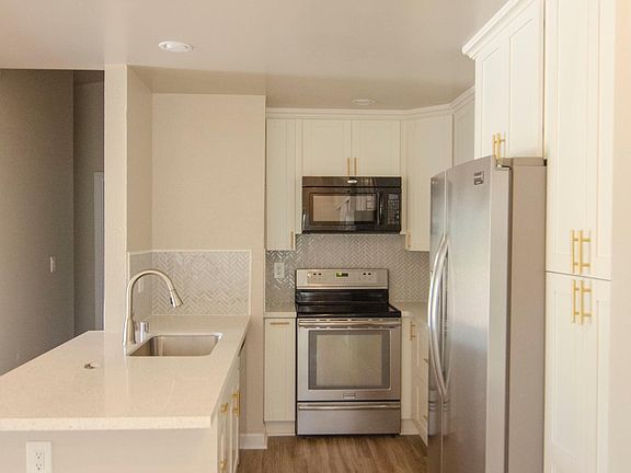 Updated kitchen with quartz countertop and white shaker cabinets, herringbone backsplash and deep sink. Upgraded appliances include refrigerator, range, dishwasher and microwave.