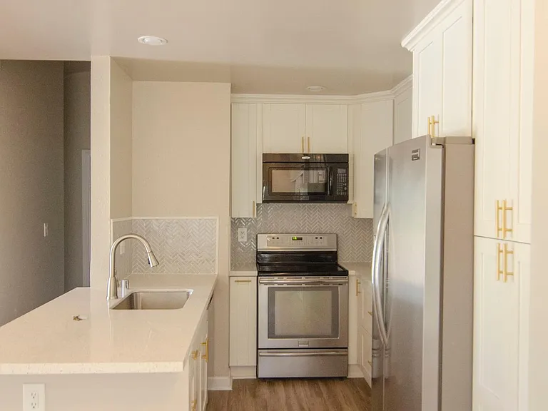 Updated kitchen with quartz countertop and white shaker cabinets, herringbone backsplash and deep sink. Upgraded appliances include refrigerator, range, dishwasher and microwave.